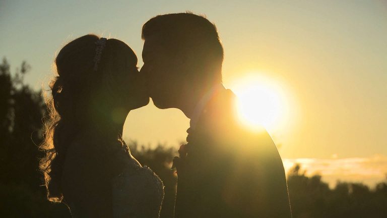 dramatic silhouette photo of a bride and groom sharing a romantic kiss during their Malkin Bank golf wedding in cheshire with their wedding videographer Love Gets Sweeter