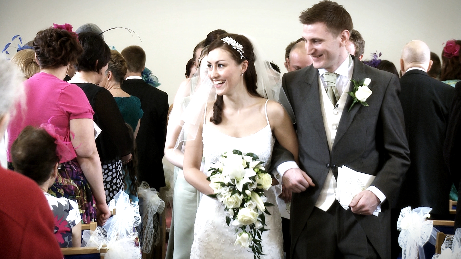a bride and groom walk back down the aisle towards their wedding videographer at a church in Cheshire with classic white tear drop flowers