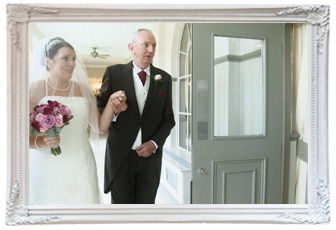 a nervous bride with her wedding veil over her face holds her dads hand before she starts to walk down the aisle at Mottram Hall