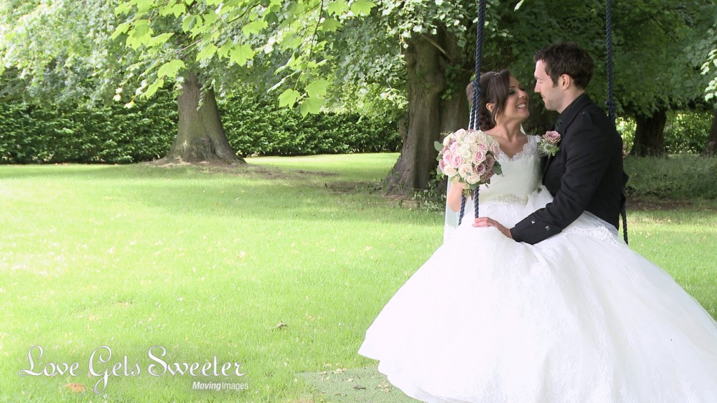 The bride and groom sit on the garden swing in the grounds of Soughton Hall as they pose naturally for the wedding photographer and videographer in Cheshire