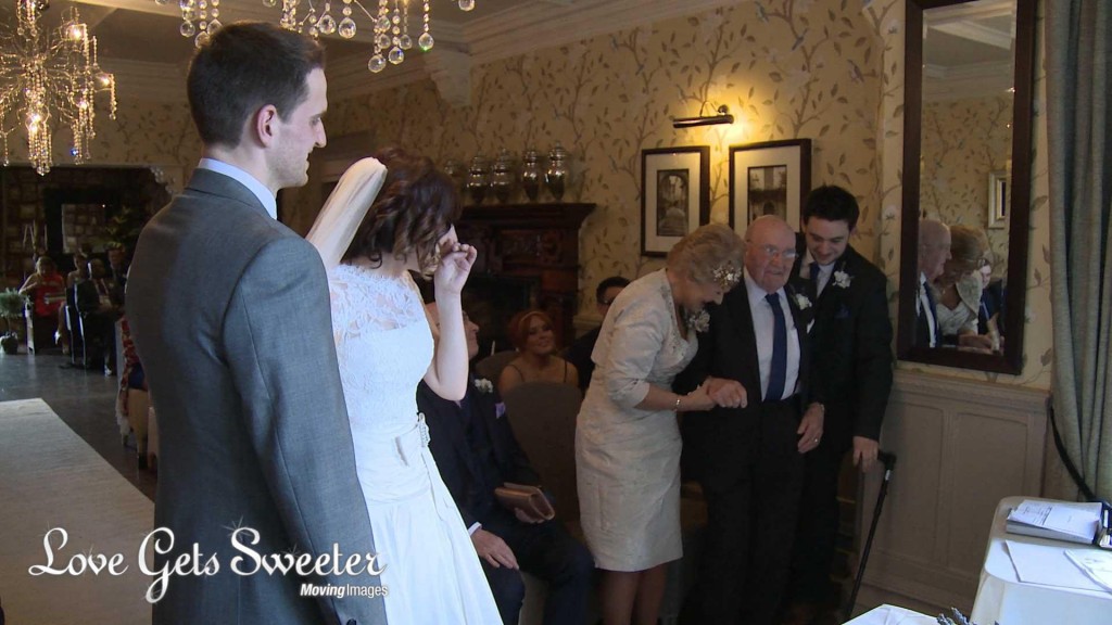 The bride Keri gets emotional as the grandad surprises her with the wedding rings during their wedding ceremony at Mitton Hall in Clitheroe. He's helped up to stand by his grandson and daughter