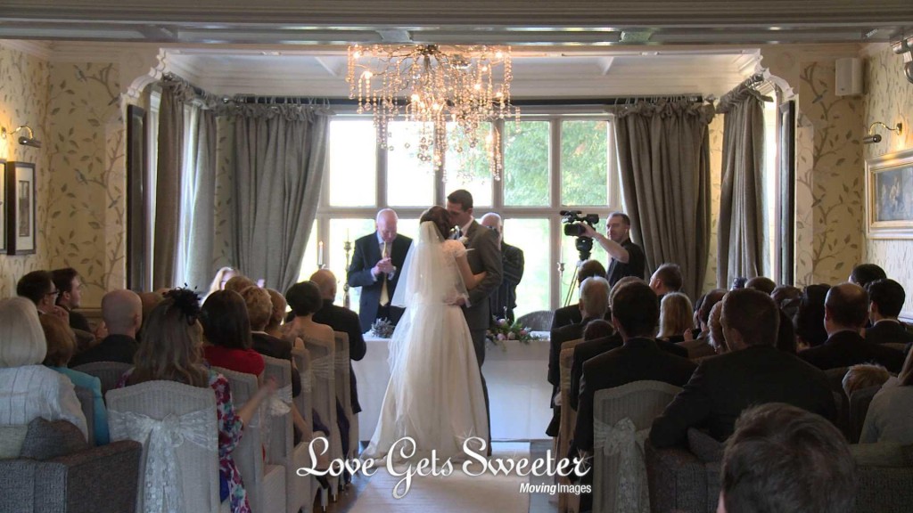 The bride and groom pull each other close and have a kiss as they're announced husband and wife in front of their guests, wedding photographer and videographer too, at Mitton Hall in Clitheroe Lancashire
