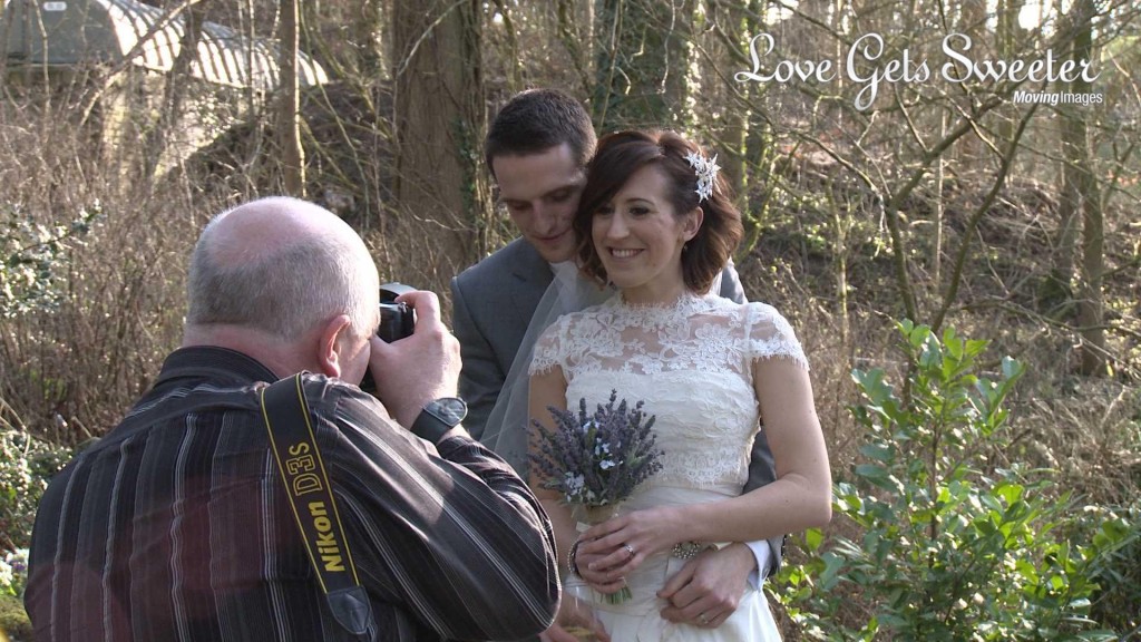 a video still of Mick Cookson the wedding photographer posing and taking photos of a bride and groom in the gardens at mitton hall