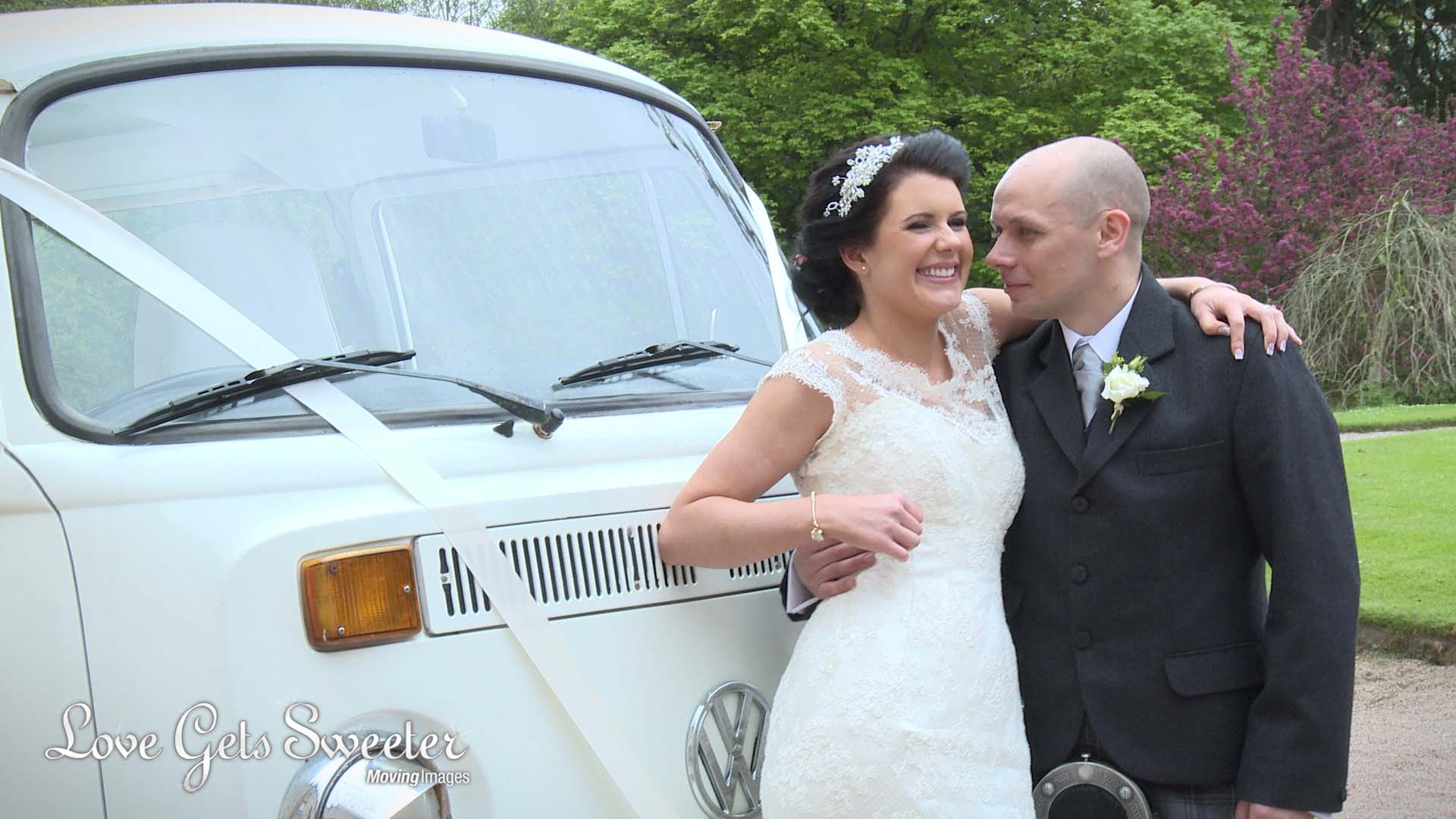 a bride and groom cuddle for their wedding photographer and videographer in the grounds of drum castle beside their cream VW camper van
