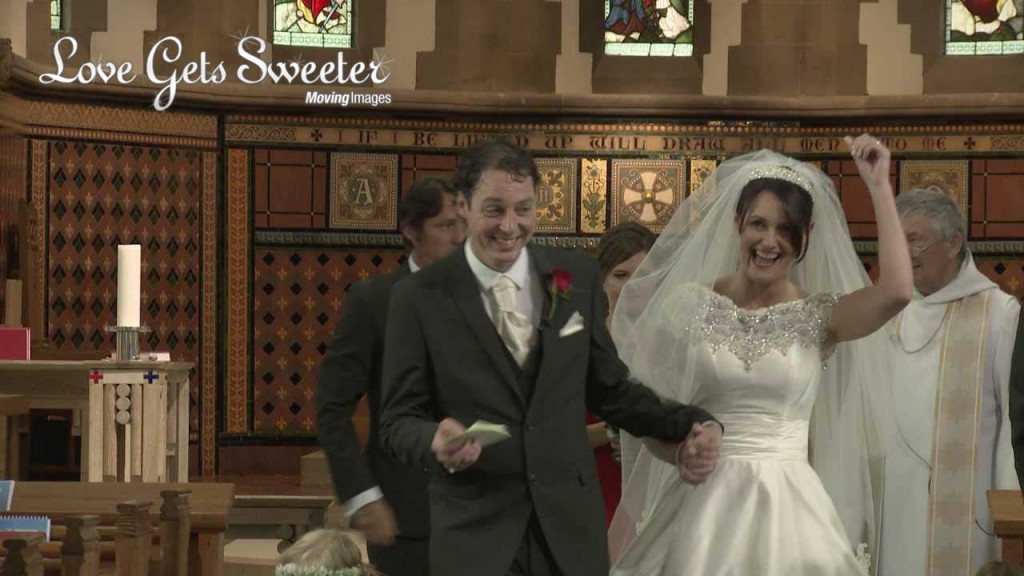 the bride punches the air for the wedding video as they both walk back down the aisle after their wedding ceremony at Dalton Church in Lancashire before heading to their reception at West Tower
