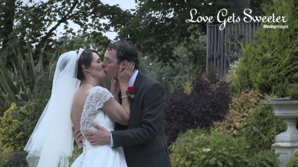 A bride holds her groom tightly as they enjoy a kiss for the wedding photographer and videographer outside West Tower in aughton Lancashire. Her silk and beaded wedding dress with a low back goes with her classic theme
