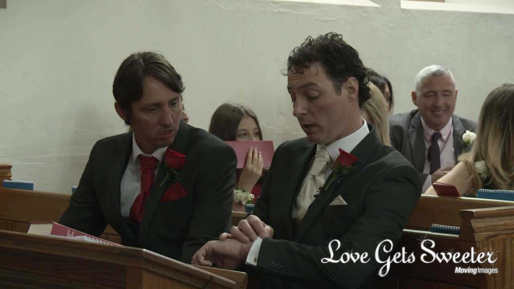 The groom sits next to his best man in a pew at Dalton St Micheal and All Angels church looking at his watch before the bride arrives for their wedding ceremony