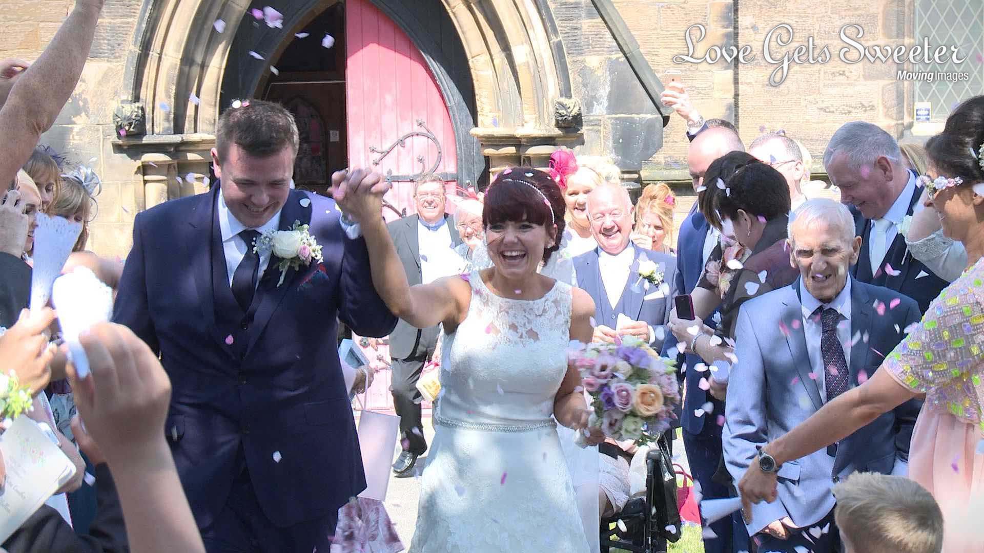 The bride and groom walk towards the Wedding videographer as guests shower them with confetti outside their birkenhead church in the wirral