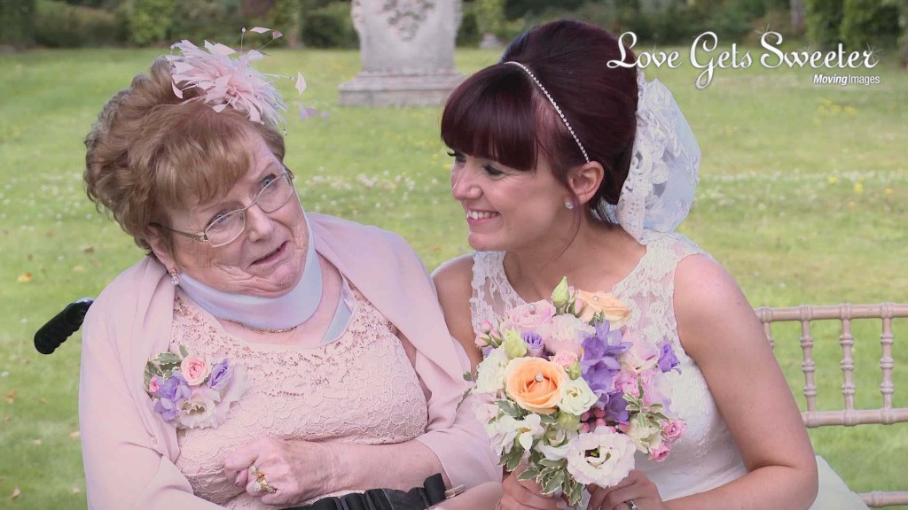 Siobhan the bride leans in to hug and smile at her Mum who is in a wheelchair as they have wedding photos done at Thornton Manor