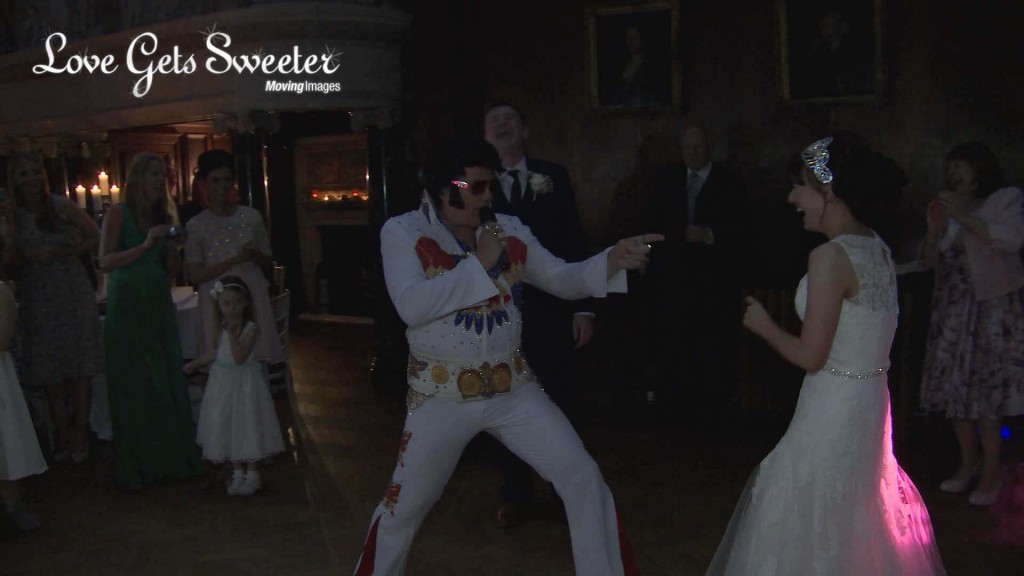 The bride and groom laugh as the surprise Elvis impersonator performs for their wedding first dance at Thornton Manor in the wirral. This is a still taken from their wedding highlights video
