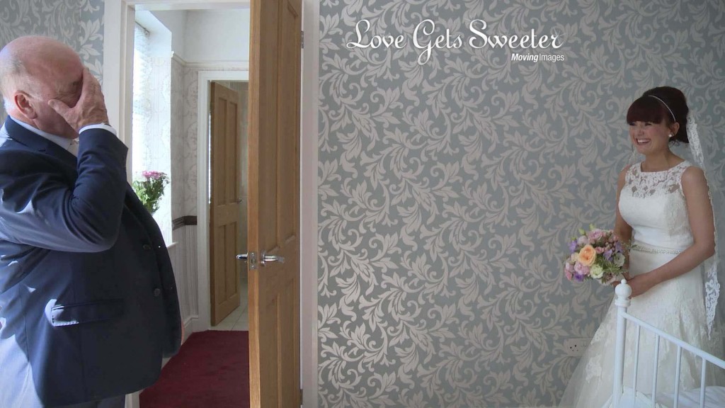 the father of the bride puts his hand to his eyes and reacts as he sees his daughter as a bride for the first time as the wedding videographer captures the emotional moment of dad and daughter