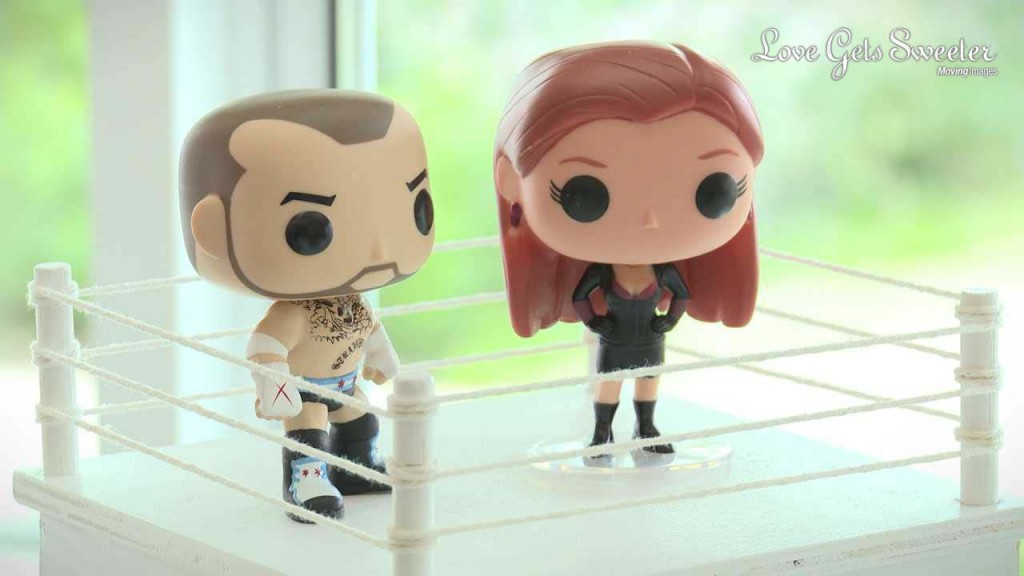 A wedding video still of a really fun wrestling inspired bride and groom cake topper inside a mini wrestling ring at a wedding at Rowton Hall
