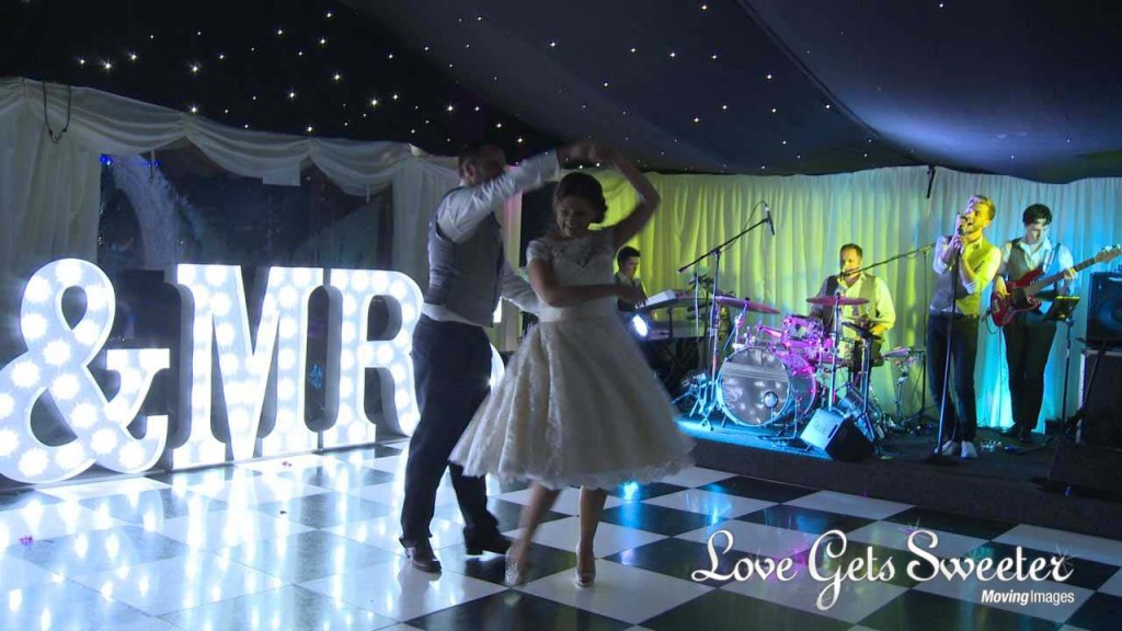 first dance at Soughton Hall in front of Mr and Mrs light up letters and the groom twirls his bride to make it a bit more fun as the band perform Take That for them