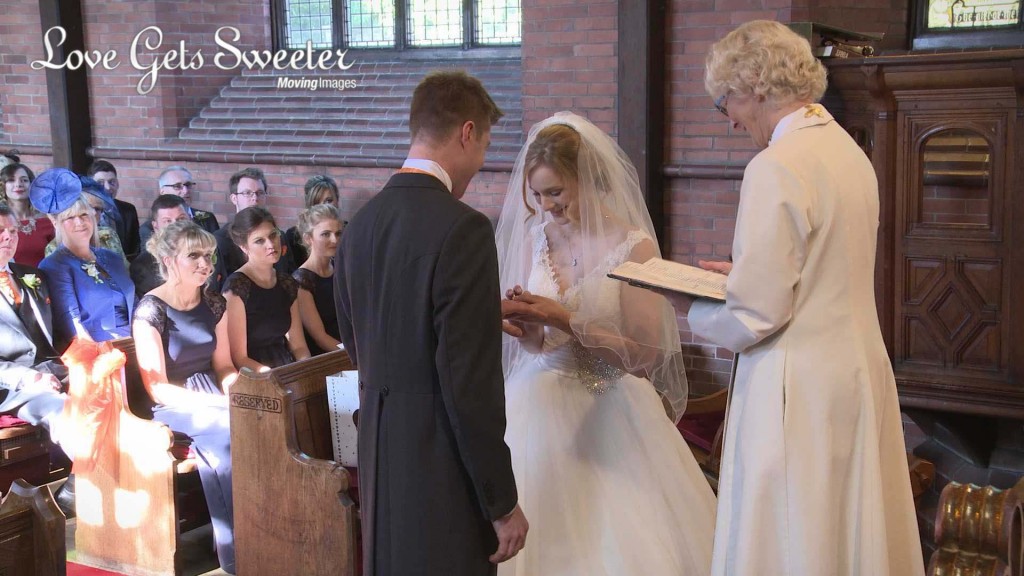 the beautiful bride emma places the ring on her grooms finger during their wedding ceremony at St Johns Church in Cheshire