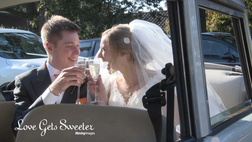 the bride and groom grin at each other as they clink champagne glasses and say cheers inside their Horgan wedding car