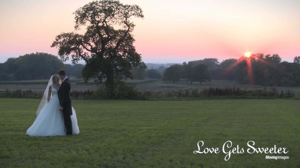 A still from the wedding video of the wedding videographer filming the bride and groom enjoying some time together at dusk in front of a beautiful sunset outside Willington Hall in Tarpoley Cheshire