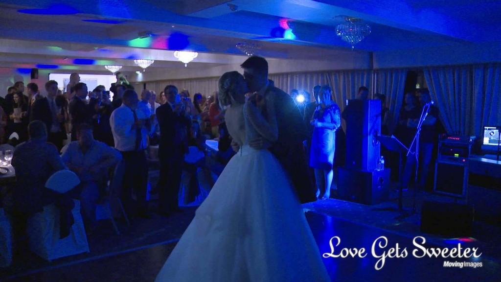 a still from the wedding video of the bride and grooms first dance at their Willington Hall wedding. They enjoy a kiss as everyone cheers