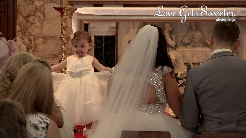 A cute flower girl is caught on the wedding video posing for the wedding guests by twirling in her dress at St Peters Church near Manchester