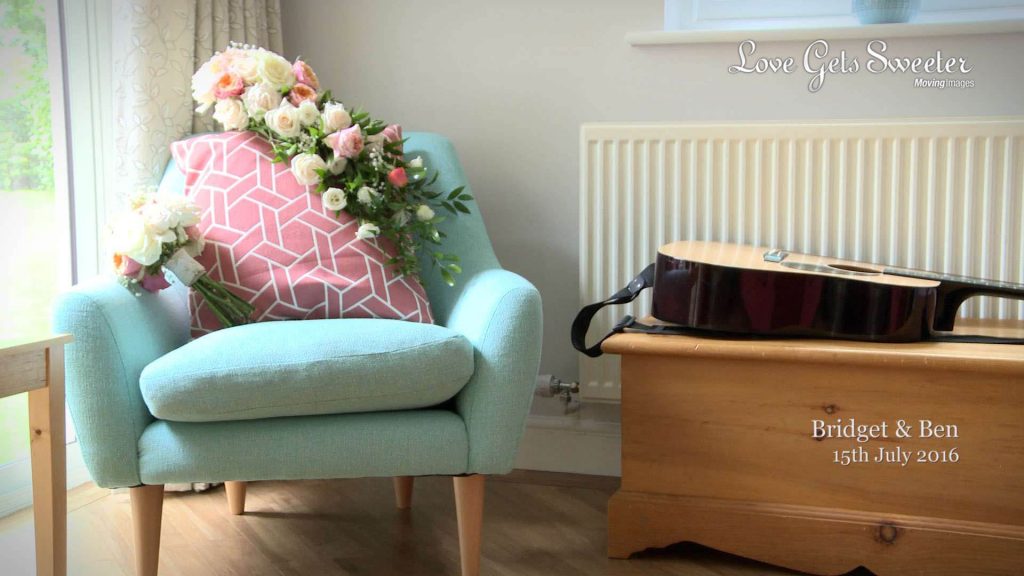 The brides traditional teardrop shaped bridal bouquet of white and pink roses sits on a bright turquoise chair next to the mother of the brides guitar to show how musical they are as a family