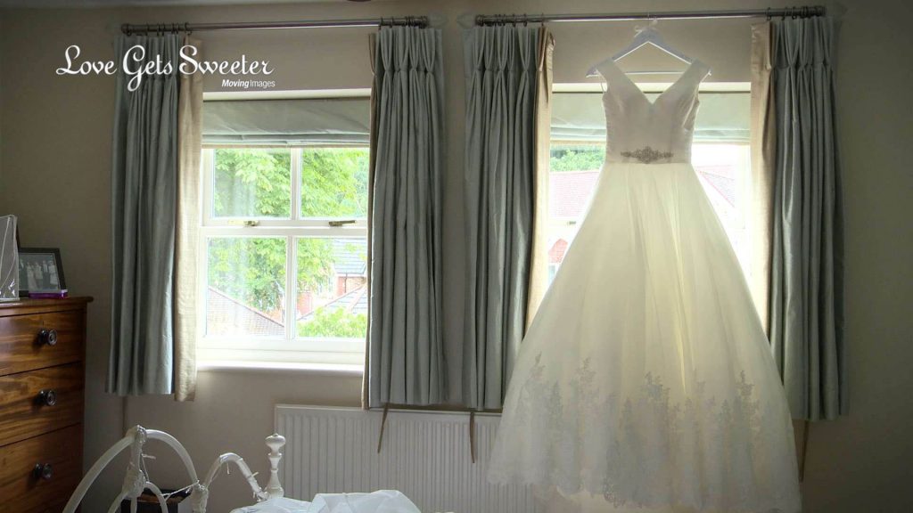 The brides traditional wedding dress with lace applique detailing hangs in the window of her parents house near Preston in Lancashire