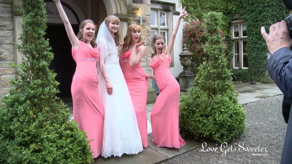 the bridesmaids dressed in full length pink dresses pull funny poses or the wedding photographer outside mitton hall