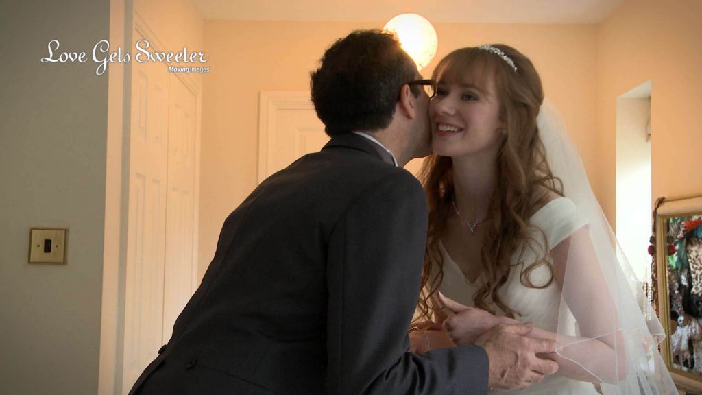 our young red head bride gets a kiss from her dad as he sees her for the first time before she gets married 