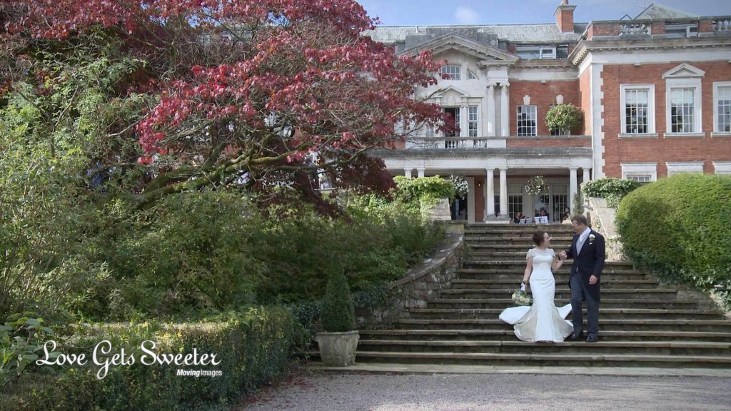 bride and groom walking around the summer gardens in front of Eaves Hall in Cheshire for the female wedding videographer