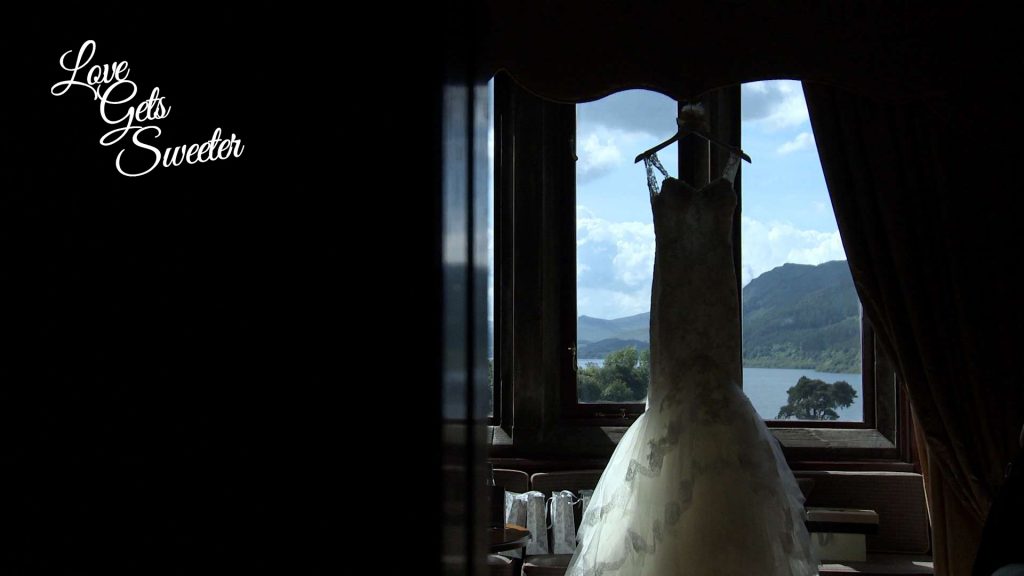 Pronovias fish tail lace wedding dress hanging in the window of Armathwaite Hall looking out to the lake district