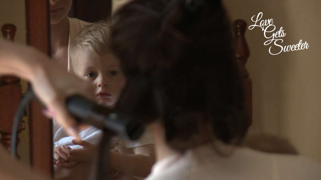 page boy sitting on the knee of a bridesmaid while she gets her hair done at Armathwaite Hall