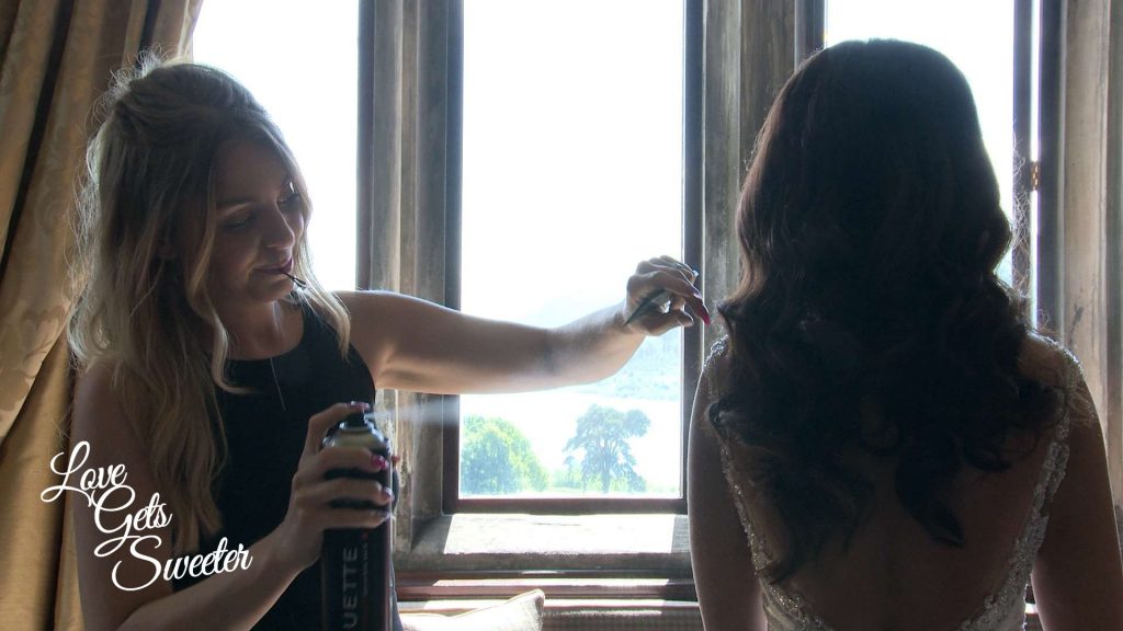 wedding hair stylist perfecting the brides hair after she's dressed and before the wedding ceremony