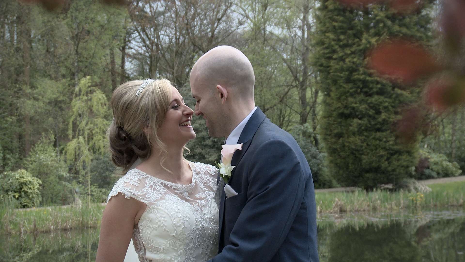 bride and groom having a cuddle and kiss beside the lake at Moddershall Oaks wedding venue for their wedding video