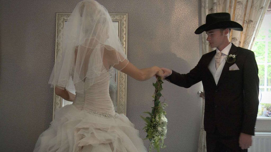bride wearing her Ian Stuart dress and holding her flower ring before getting married at St Pauls in drighlington for the wedding video