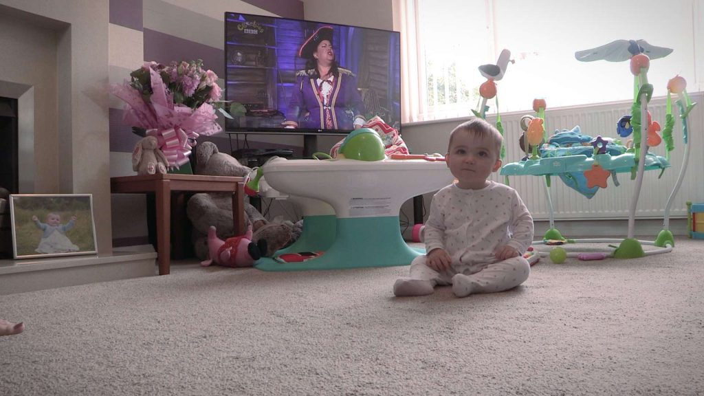 baby girl sat in her living room waiting for her mummy and daddy on video for her own christening video