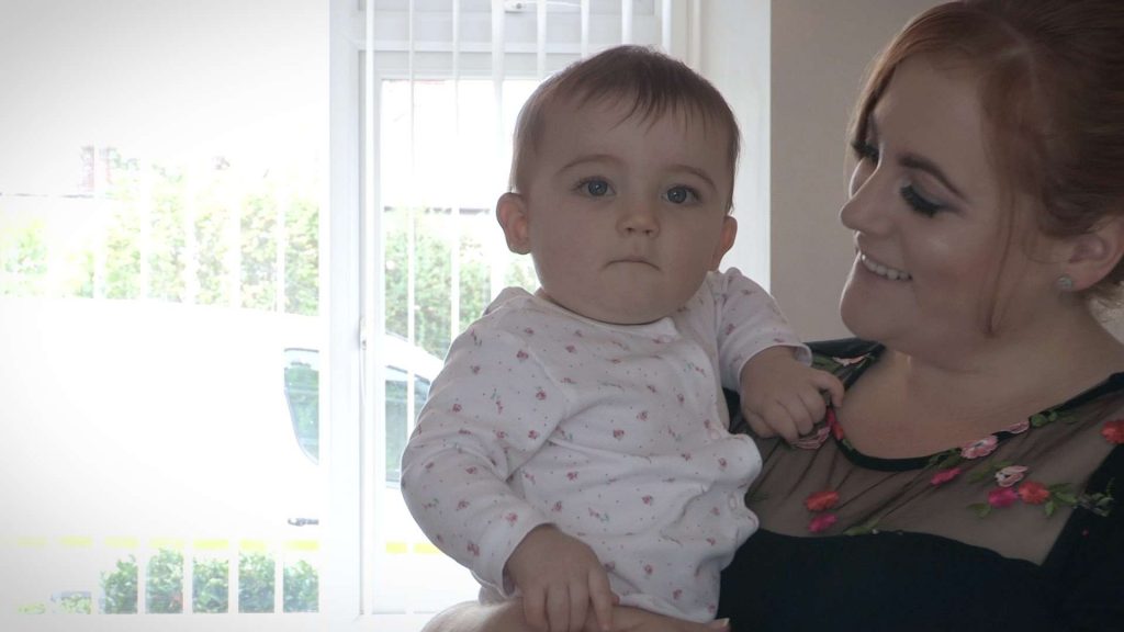 baby girl suspicious of the video camera before getting ready for her christening with her Mum