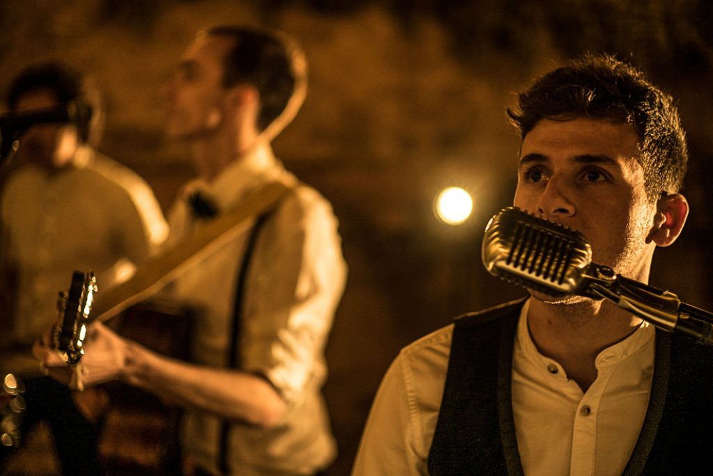 lead singer of wandering wings singing in to a retro silver microphone for a promo shoot
