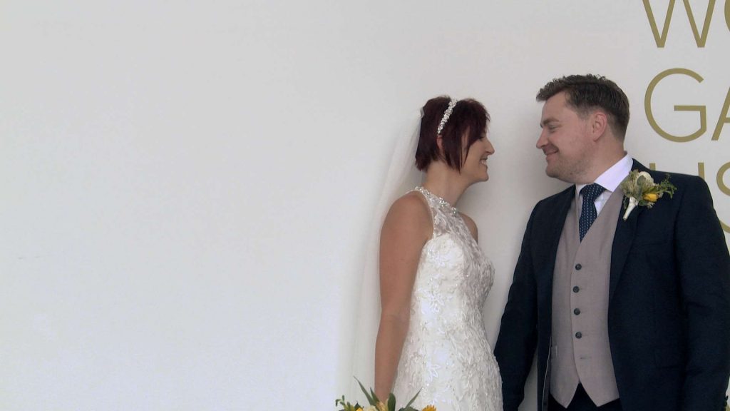 the bride and groom pose for the wedding photographer and videographer against a simple white wall at On The 7th in Media city
