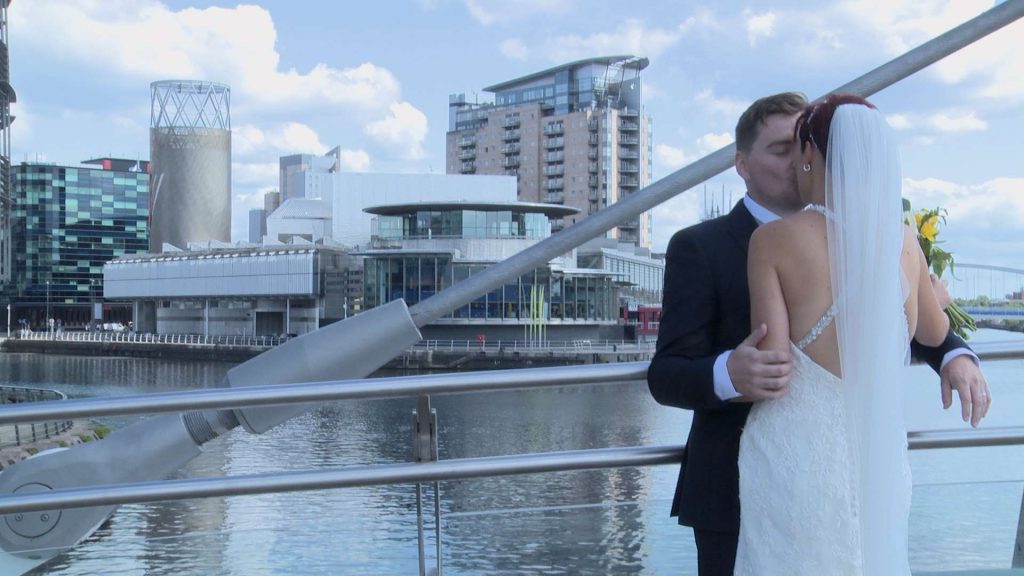 groom kisses his bride on the lowry bride in Salford