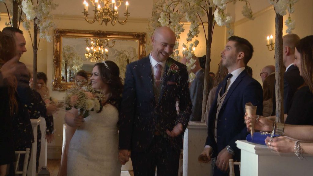 The beaming bride and groom walk back up the aisle now married at their christmas wedding at Nunsmere hall