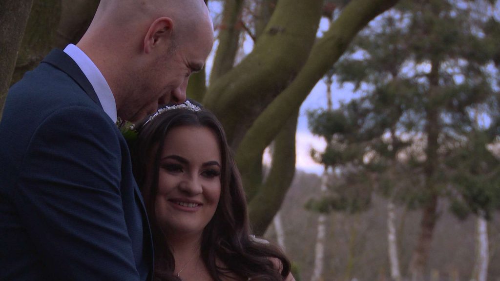 the bride and groom chat near the line of trees at Nunsmere hall