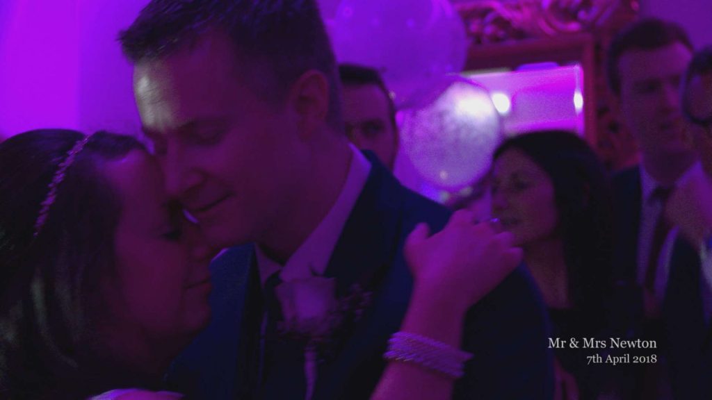 guests sing along behind the couple as they have their first dance during their wedding reception in the lake district