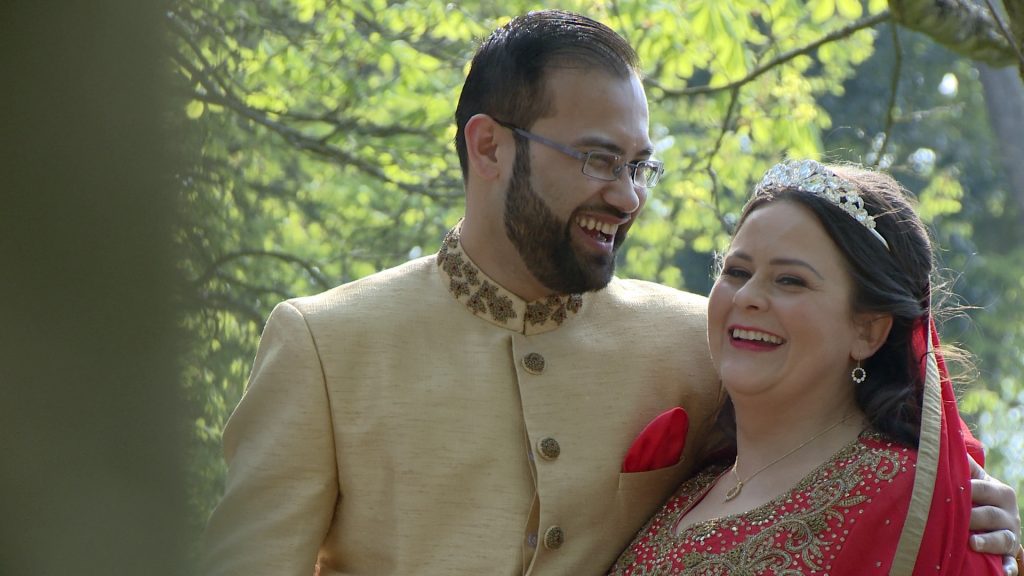 the bride and groom laugh with the wedding photographer and videographer as they enjoy photos in the Botanic gardens after their wedding in southport