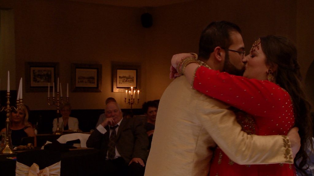 a bride and groom in traditional bangladeshi wedding saree and dress enjoy a kiss and cuddle during their first dance at their southport wedding