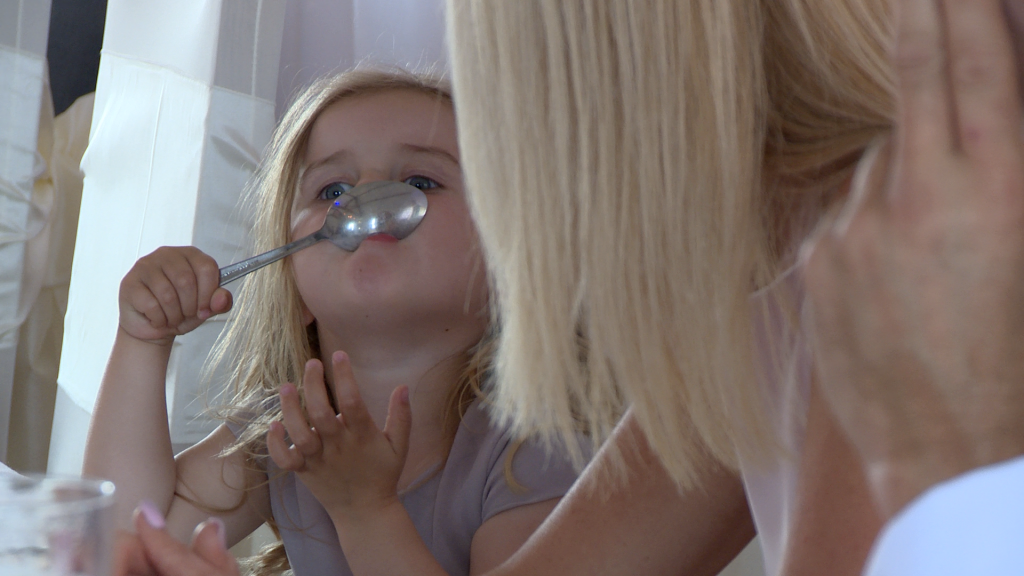 the flower girl makes her nan laugh as she tries to stick a spoon to her nose during the wedding reception at The Blue Mallard in Burscough Wharf