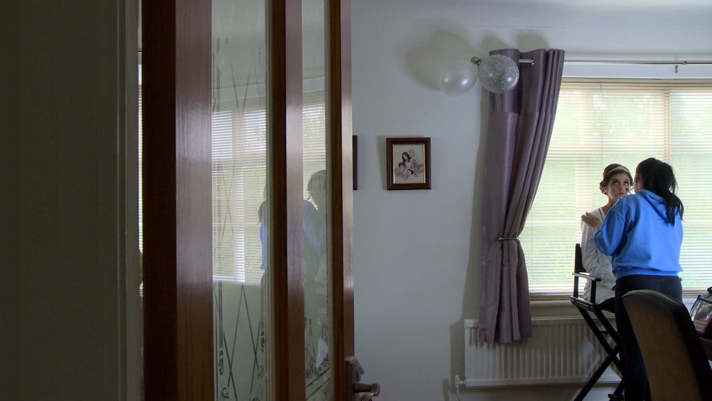 the wedding videographer looks on from the hall as the bride had her wedding make-up done by her professional make up artist Olivia Disley in the lounge of her mum and dads house in Holmeswood lancashire