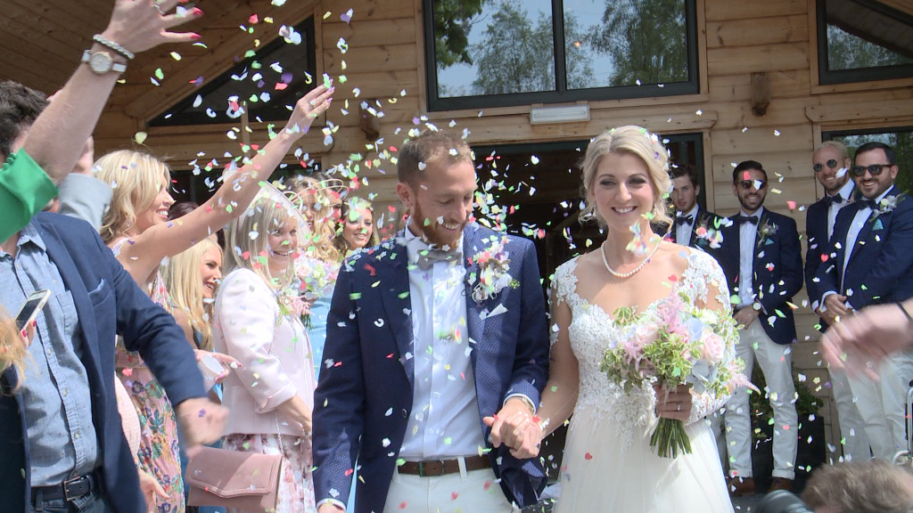 the bride and groom are showered in bright coloured natural petal confetti outside Styal Lodge in Cheshire for their wedding video