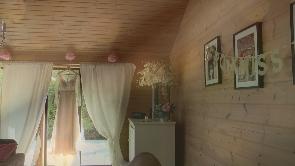 a wedding dress hangs up in the bridal room at Styal lodge ready for the bride