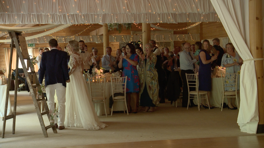 the bride and groom dance through the tables during their entrance for the wedding reception at Styal Lodge in Cheshire caught on the wedding video