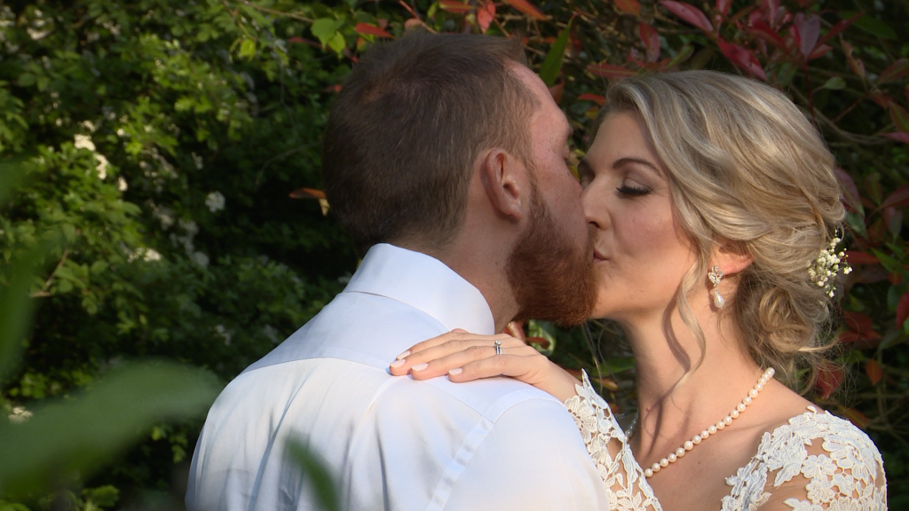 Bride and groom kiss posing for their wedding photographer and videographer at Styal Lodge in Cheshire