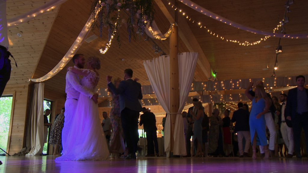 the bride and groom are joined on the dancefloor for their first dance under a floral hoop and festoon lights at Styal Lodge in Cheshire