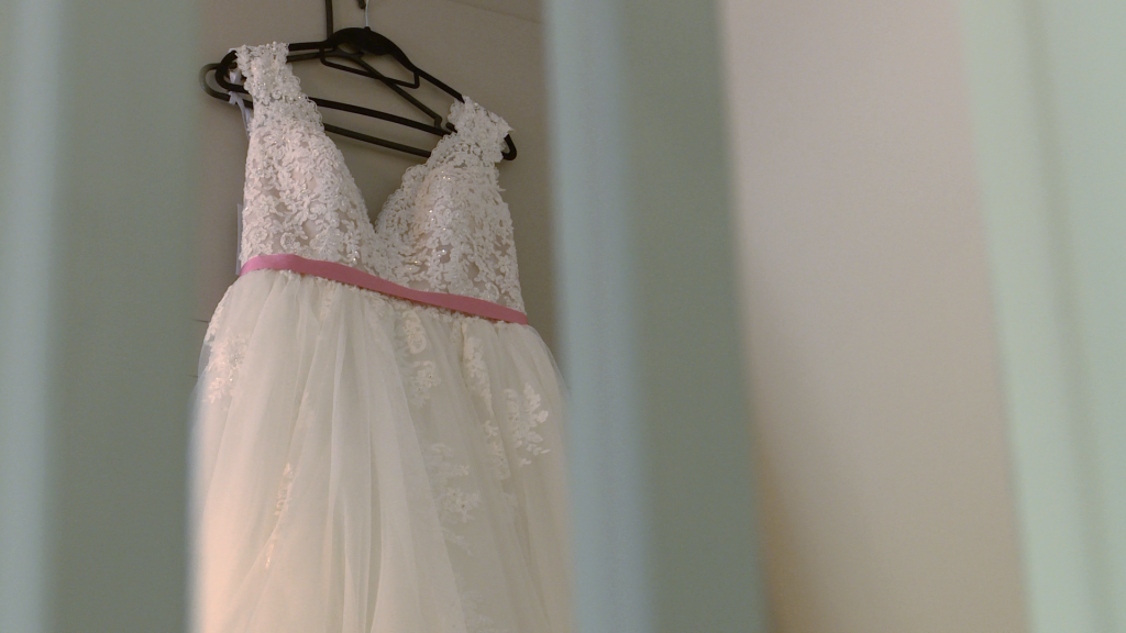 a wedding dress hangs in a bedroom with the door open from the stairs at a cottage at thornton manor